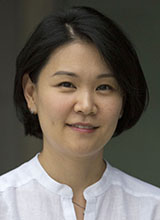 A woman with short dark hair wearing a white shirt,