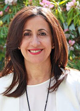 Woman with brown hair, wearing a white top