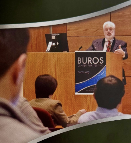 Speaker Dr. Kurt Geisinger at podium with Buros Center for Testing banner addressing an audience in a conference room.