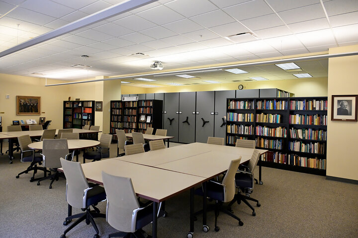 Library room with bookshelves, rolling files, tables, and chairs.
