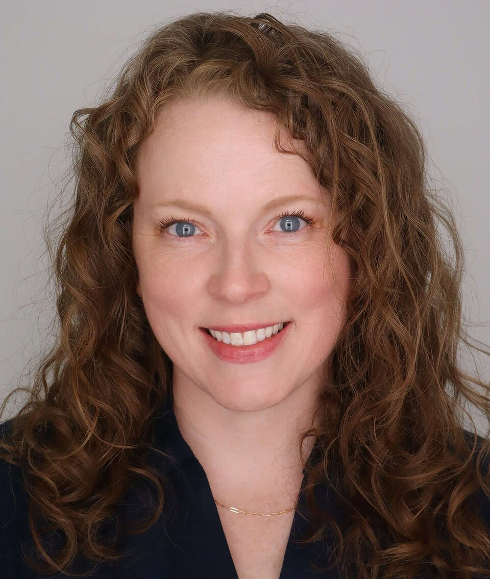 Woman with curly hair and a navy suitcoat