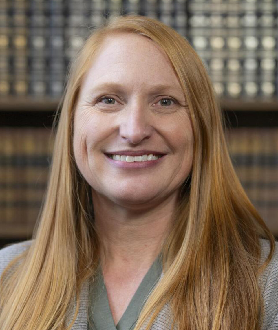 Woman n with long hair, wearing a green shirt and blazer